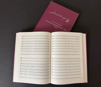 Ein aufgeschlagenes Buch liegt schräg auf einem geschlossenen Buch, mit weinroten Einband. Ein aufgeschlagenes Buch liegt schräg auf einem geschlossenen Buch, mit weinroten Einband.